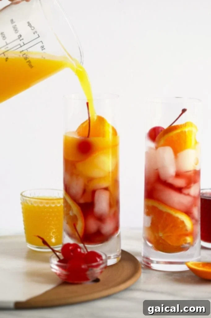 Orange juice being poured into a Sex on the Beach cocktail glass, creating beautiful layers of color.