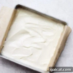 Cheesecake bars showing the smooth, plain cheesecake layer spread over the crust before baking.
