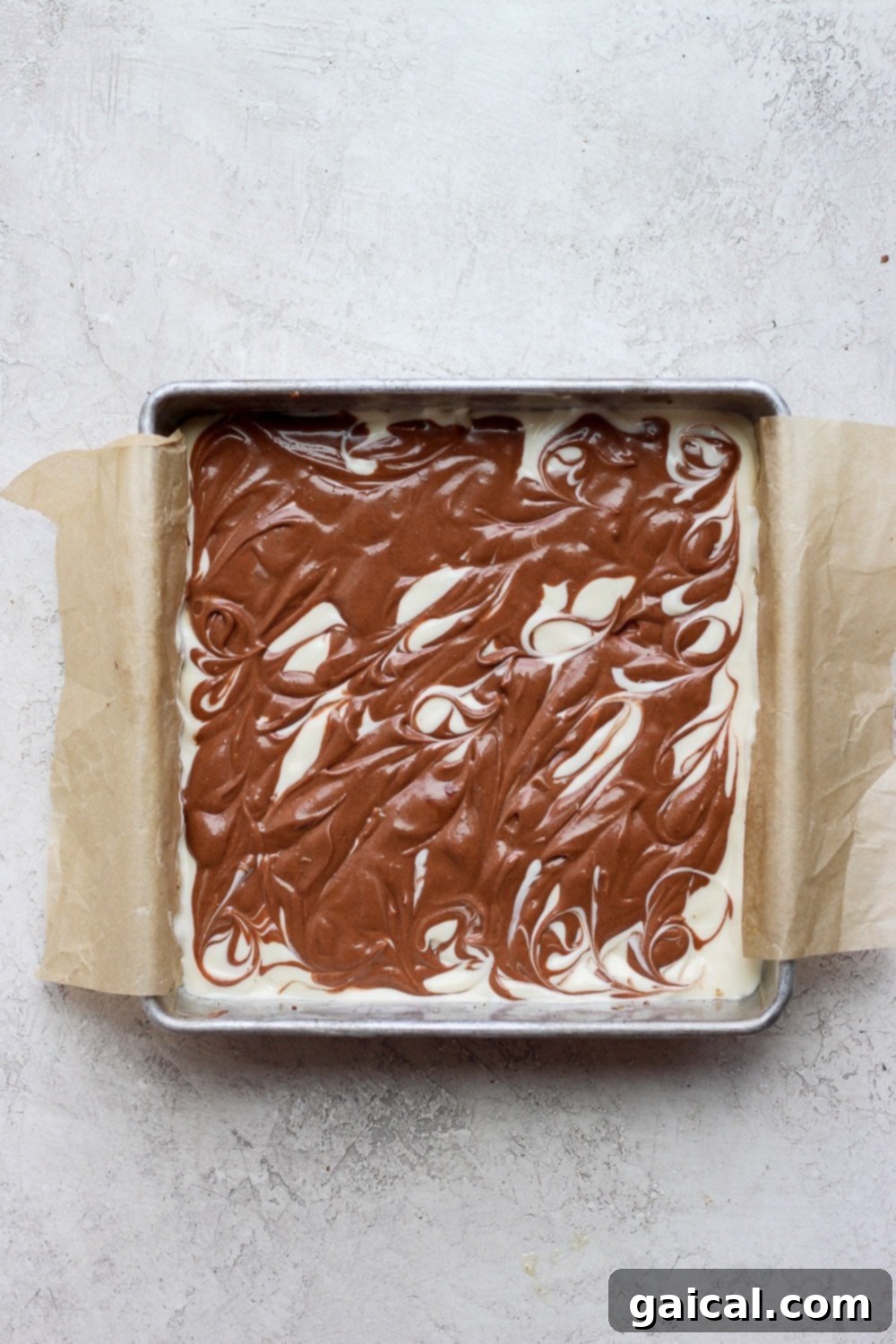 Unbaked chocolate chai cheesecake bars showing the intricate chocolate swirl pattern on top.