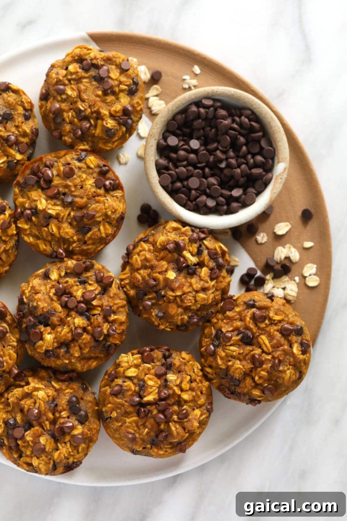 Spiced Pumpkin Oat Cups 2 Delicious pumpkin oatmeal cups adorned with mini chocolate chips on a rustic tray, ready to be enjoyed as a healthy fall snack.