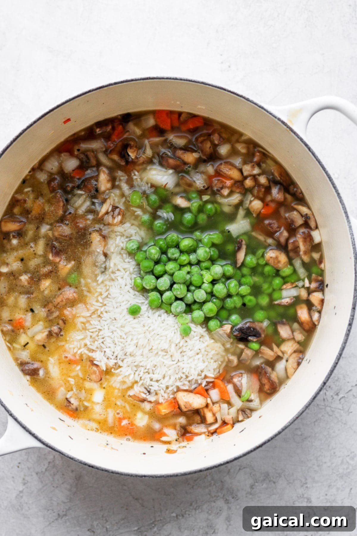 A flavorful chicken and rice recipe made with juicy chicken thighs and the most flavorful rice medley you've ever had! And, yes, it includes tons of veggies! Uncooked basmati rice and mixed vegetables simmering in a stockpot before adding chicken.
