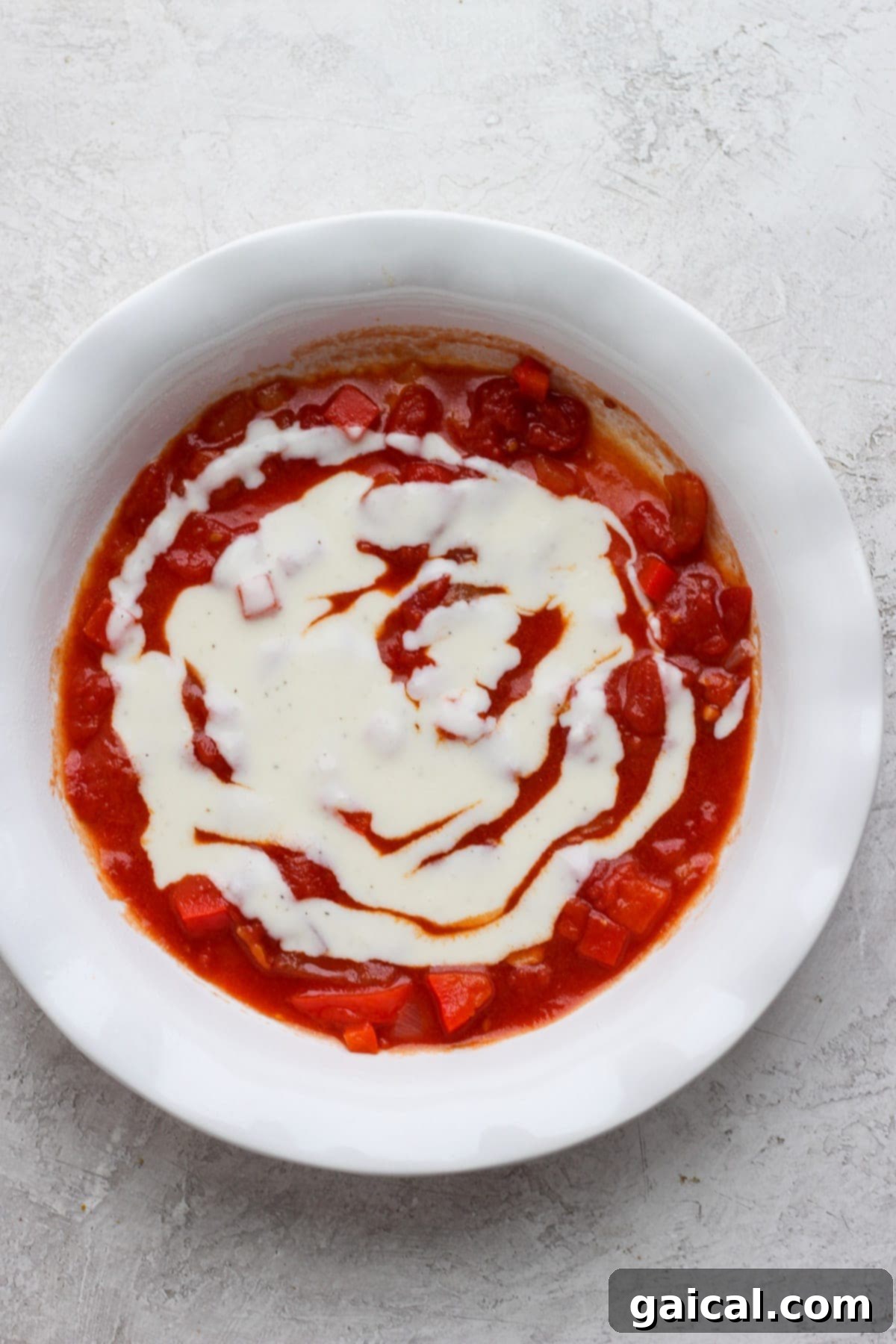 Layers of red tomato sauce and white béchamel sauce spread at the bottom of a baking dish.