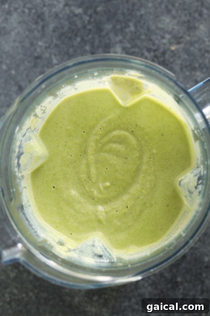 Cheesy Broccoli Cauliflower Delight 5 A vibrant green, smooth liquid in a blender, representing the lightened-up broccoli cheese soup.
