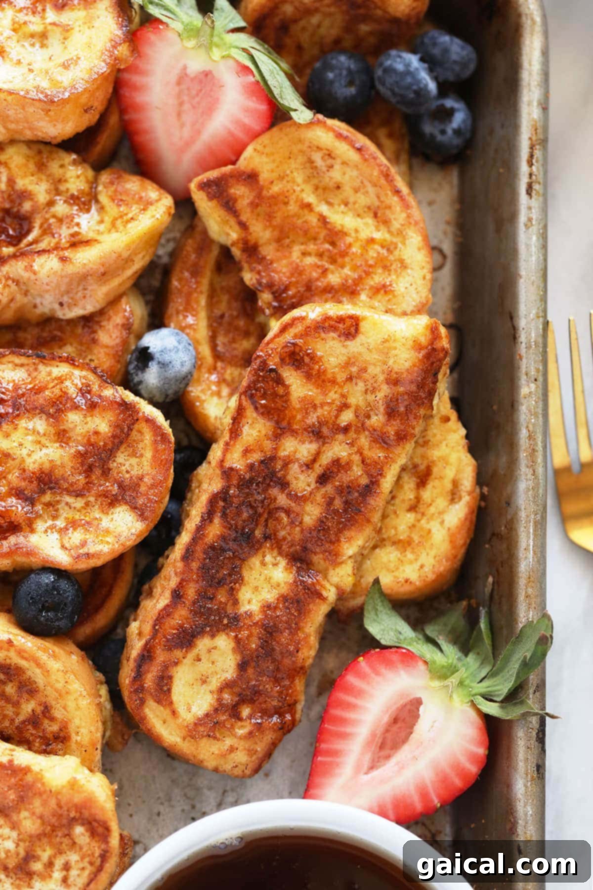 A platter of golden French Toast Sticks garnished with fresh strawberries, ready to be enjoyed as a delightful breakfast.