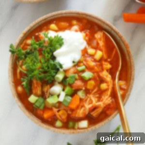 A perfectly portioned bowl of buffalo chicken chili, garnished with sour cream and shredded carrots.
