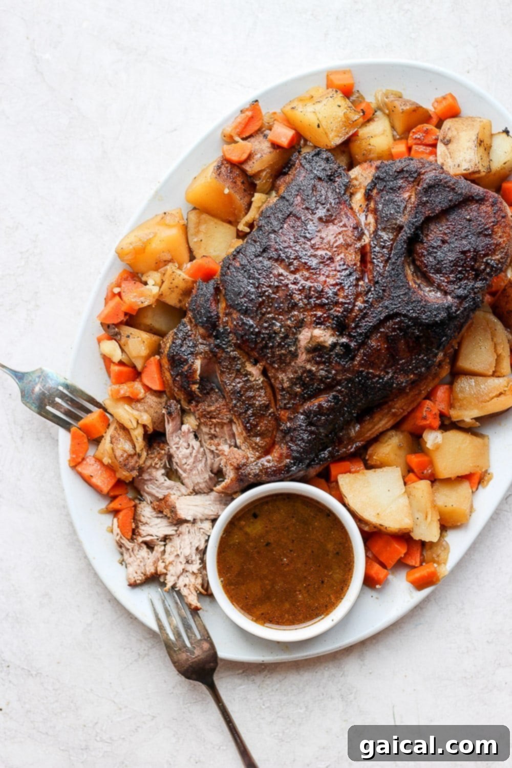 Make this pork roast in oven made with a dry-rubbed pork shoulder roast, tons of veggies, and a savory gravy. Oven baked pork roast surrounded by golden potatoes and carrots, perfectly cooked and ready to serve