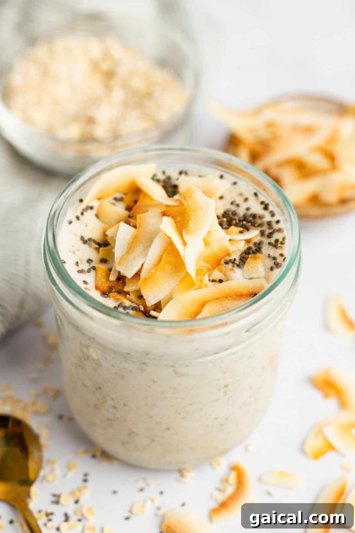 Coconut Latte Overnight Oasis 2 A glass jar filled with creamy coconut latte overnight oats, topped with toasted coconut flakes and chia seeds.