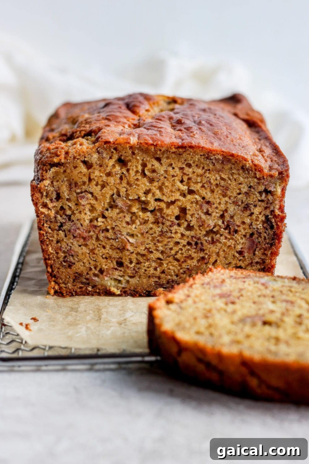 The best healthy banana bread recipe on the internet is right here! It's made with 100% whole grains, all-natural sugars, and coconut oil. Make it today! A perfectly baked loaf of healthy banana bread with a slice cut out, showcasing its moist texture.