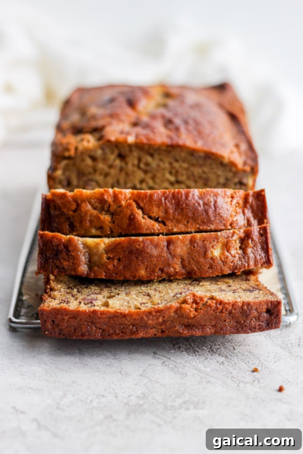 Delicious, airy, moist healthy healthy banana bread coming right up! Our signature healthy banana bread recipe is made with white whole wheat flour, ripe bananas, all-natural sweeteners, and coconut oil. Slices of healthy banana bread arranged on a cooling rack, showing off their perfect texture.