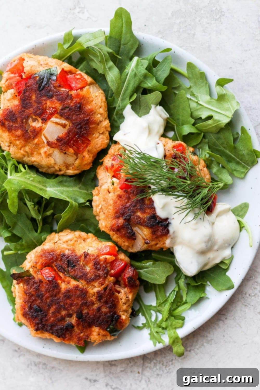 Learn how to make salmon patties with cooked flakey salmon, panko breadcrumbs, garlic, mayo, and a little tabasco. You will seriously love this salmon patties recipe! salmon patties atop arugula with tartar sauce