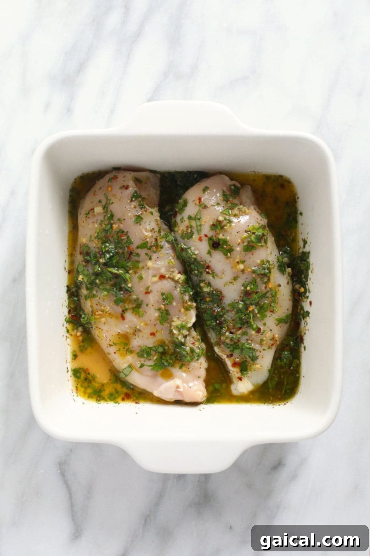 Chicken marinating to perfection for maximum flavor and tenderness. Chicken breasts perfectly submerged in the homemade Italian marinade within a glass dish, resting in the refrigerator.