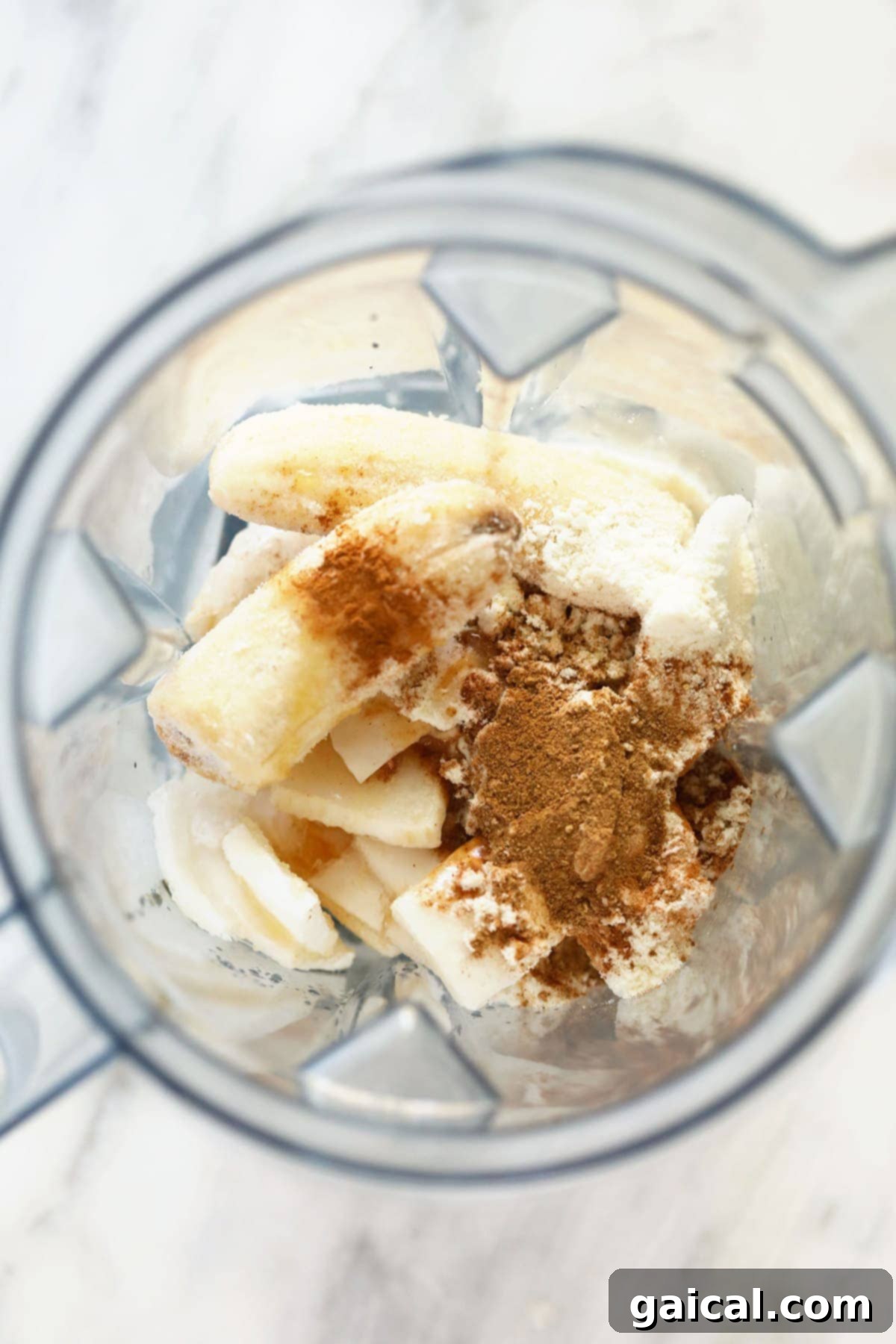 Spiced Coconut Protein Bliss 3 All the fresh and frozen ingredients for the chai protein shake, including blocks of frozen coconut meat, ripe bananas, a scoop of protein powder, and a small jar of chai spices, perfectly arranged in a high-speed blender, ready to be transformed.