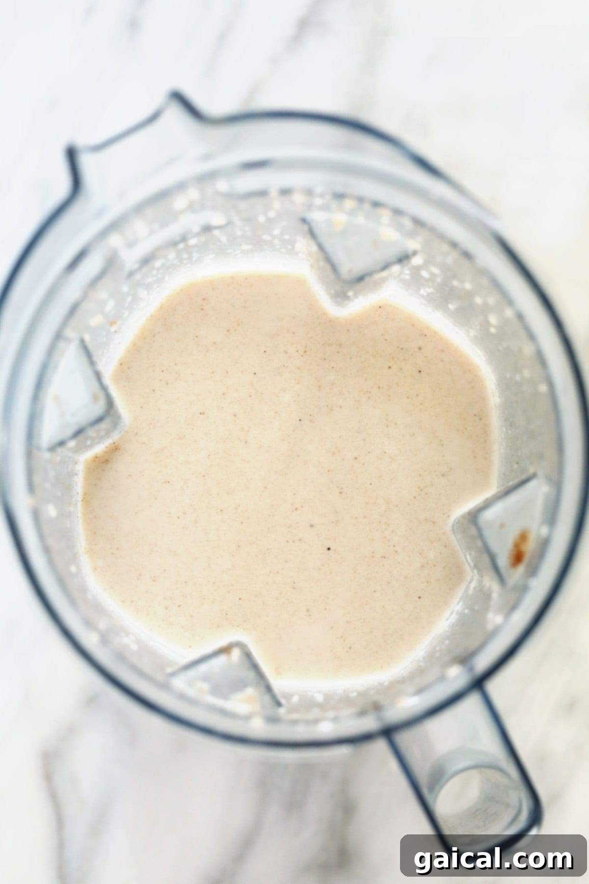 Spiced Coconut Protein Bliss 4 A vibrant, creamy chai protein shake actively being blended in a high-speed blender, showcasing its smooth, swirling texture and rich color as it mixes.