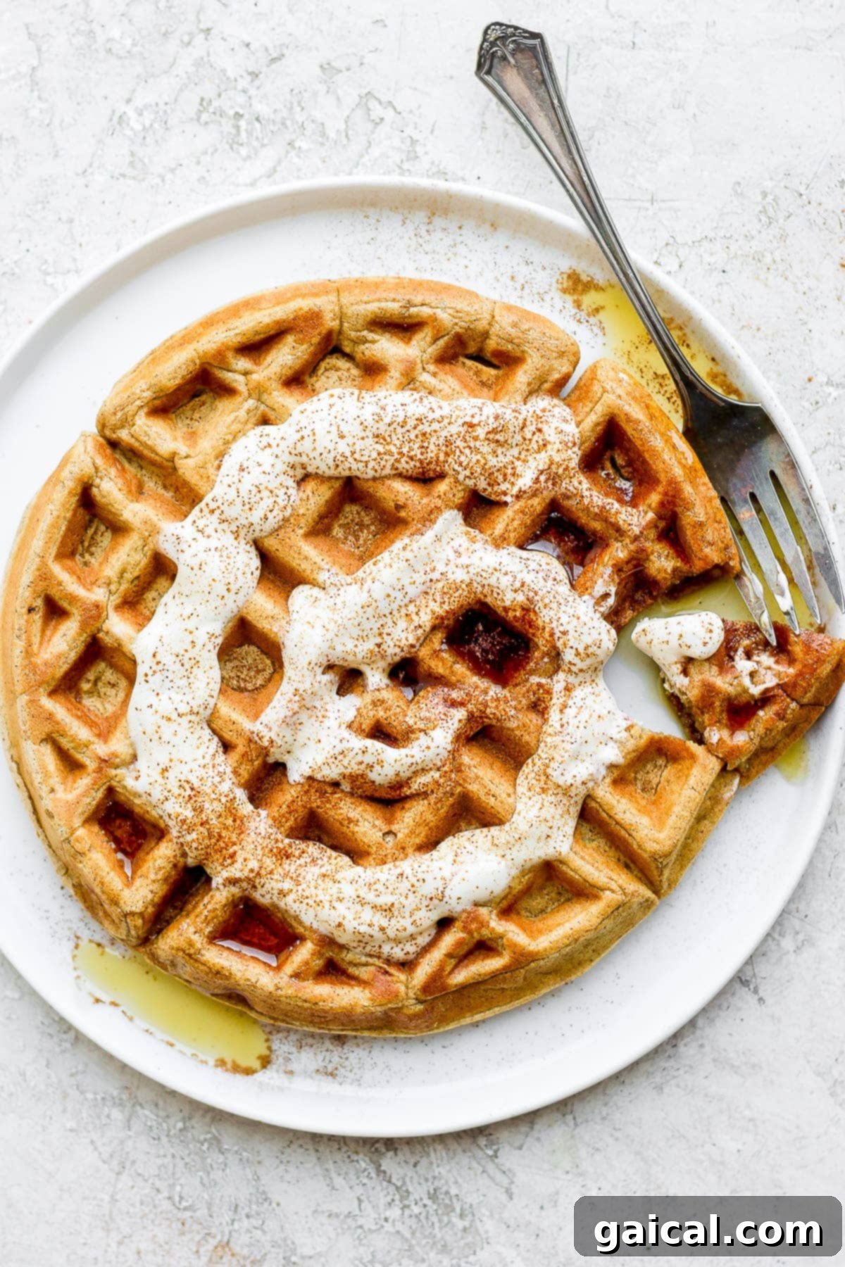 Waffled Cinnamon Rolls 2 Delicious cinnamon roll waffles topped with a creamy Greek yogurt cream cheese drizzle, garnished for a healthy breakfast.