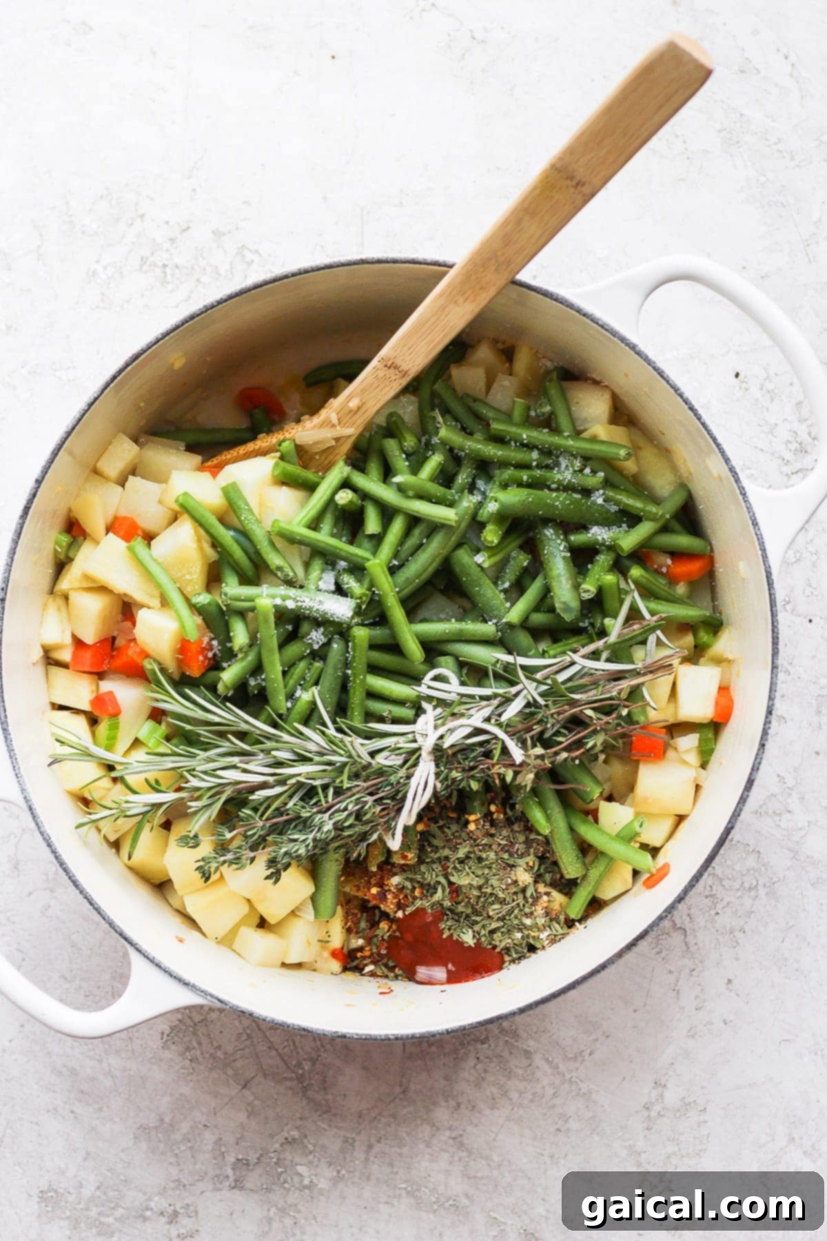 Nourishing Garden Harvest Soup 3 Fresh, colorful ingredients for a hearty vegetable soup, including diced potatoes, carrots, celery, and herbs, arranged in and around a large Dutch oven.