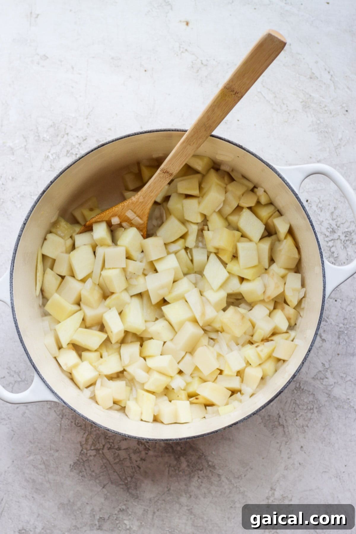 Nourishing Garden Harvest Soup 4 Diced potatoes, onions, and minced garlic sizzling in olive oil within a vibrant red Dutch oven, forming the aromatic base of the soup.