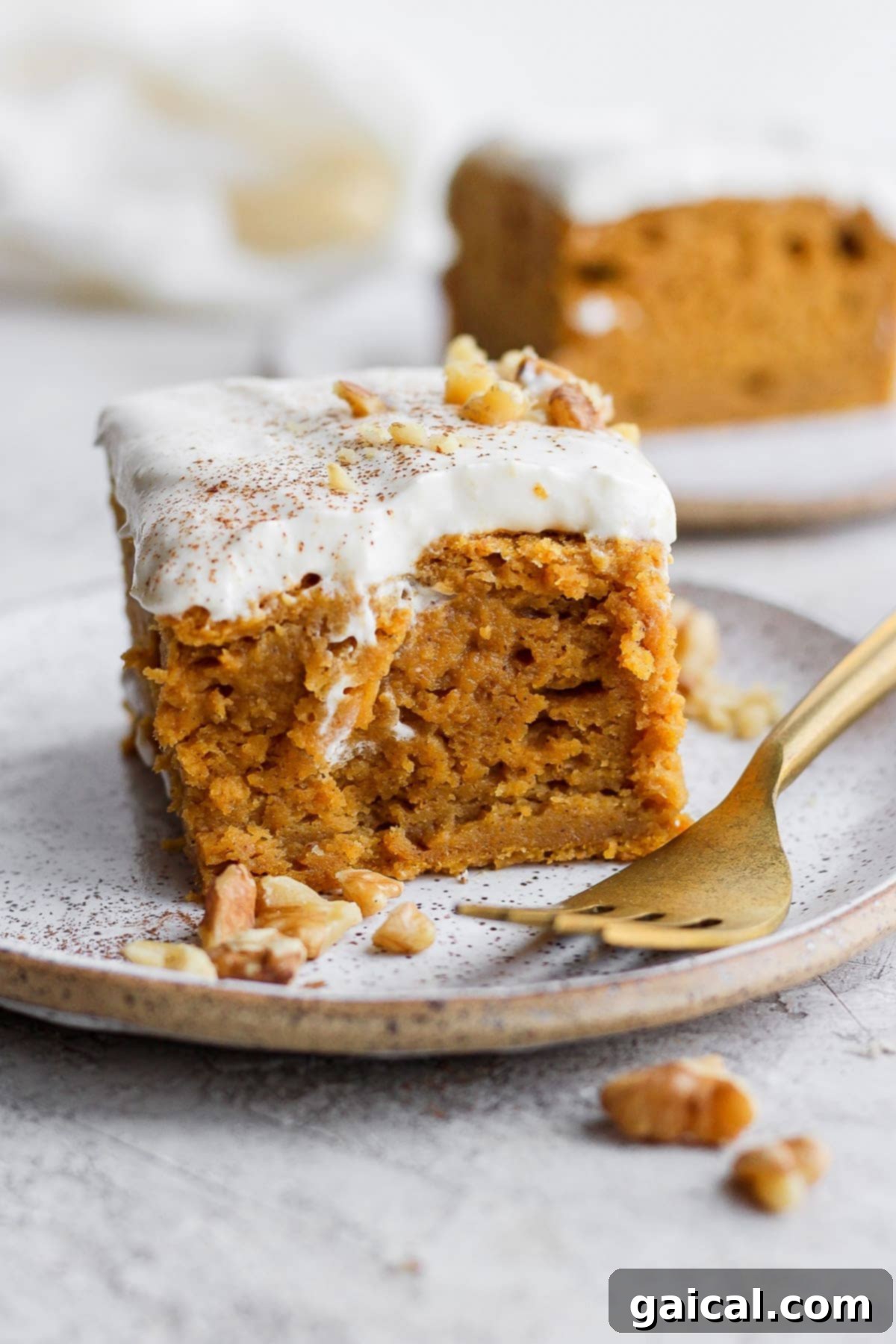 Sheet Pan Pumpkin Perfection 2 A perfectly sliced piece of pumpkin sheet cake topped with creamy frosting, resting on a white plate, ready to be enjoyed.