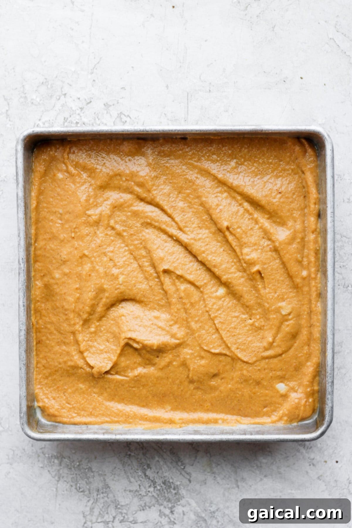 Sheet Pan Pumpkin Perfection 4 Smooth, orange pumpkin sheet cake batter poured evenly into a square baking pan, ready for the oven.