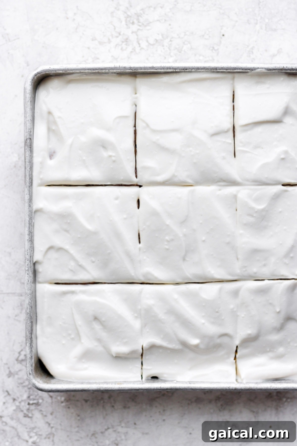This pumpkin sheet cake is as easy as it is delicious. Packed with simple ingredients and topped with a yummy cream cheese frosting, this dessert can't be beat! A beautifully frosted pumpkin sheet cake, topped with a thick layer of smooth cream cheese frosting, ready for slicing.