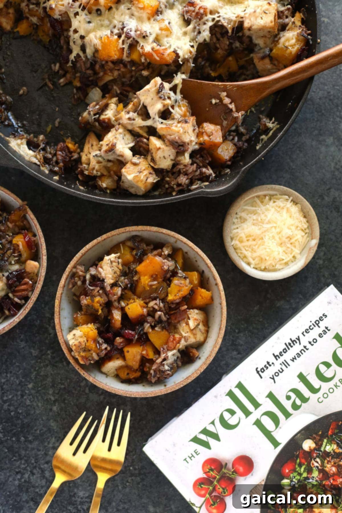 Butternut Squash Wild Rice Casserole scooped from a cast iron pan, showing its hearty ingredients and golden-brown top.
