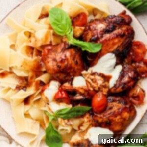 Grilled balsamic chicken thighs served with pappardelle pasta and roasted cherry tomatoes on a plate.