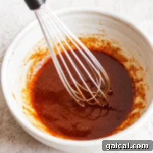 A bowl of sauce with a whisk in it, showcasing the freshly mixed marinade.