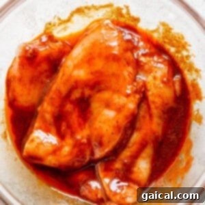 A bowl of chicken with sauce in it, showing the chicken soaking in the marinade.