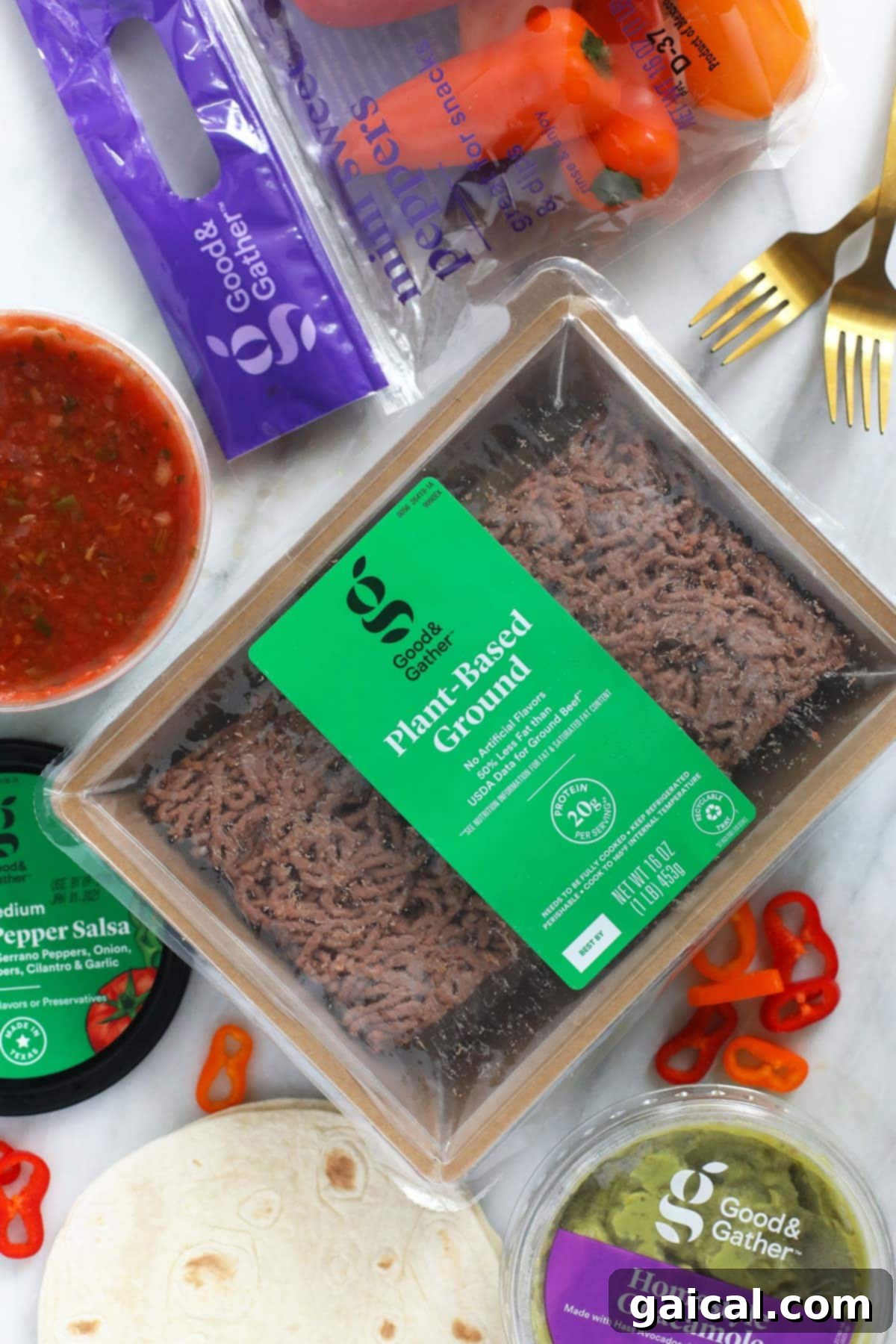 Essential Good & Gather Ingredients for Vegetarian Tostadas Arrangement of fresh tostada ingredients including plant-based ground, creamy guacamole, corn tortillas, spicy salsa, and colorful mini sweet peppers on a rustic wooden board.