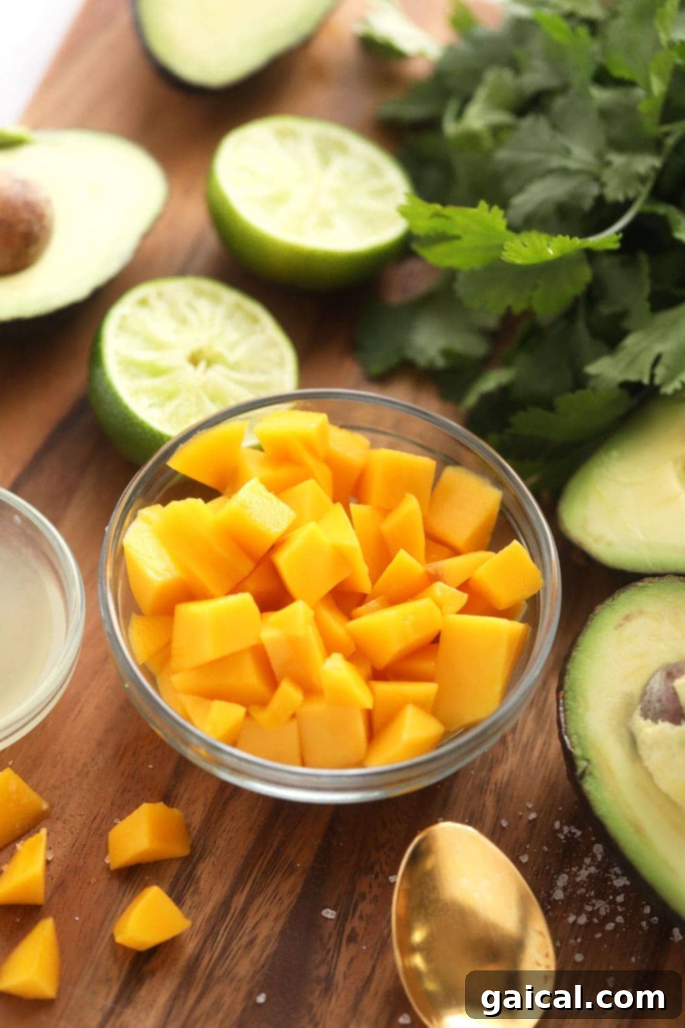 Freshly sliced, vibrant orange mango cubes are carefully arranged in a small white bowl, glistening and ready to be incorporated into a delicious tropical guacamole recipe.