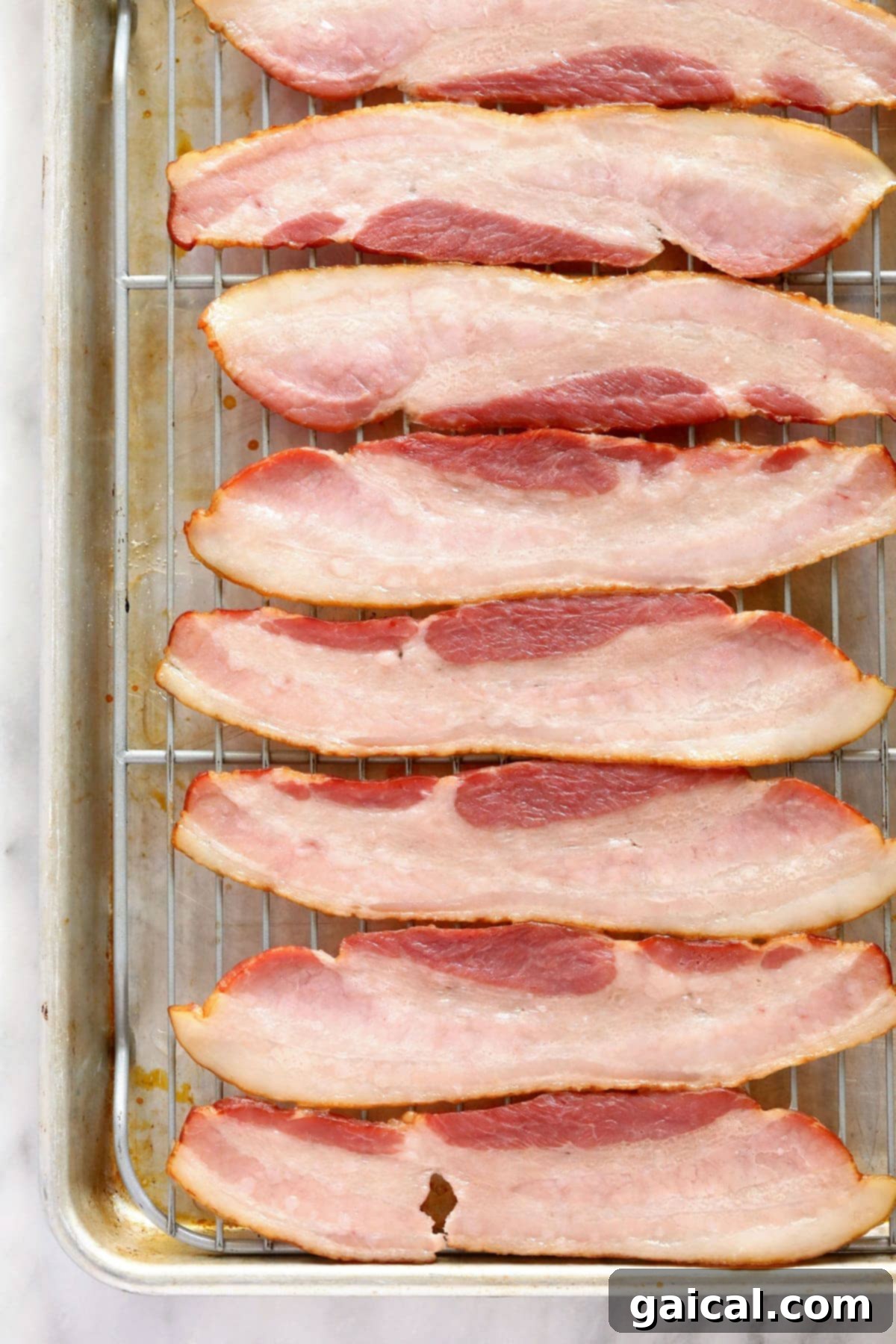 Preparing Thick-Cut Bacon for Wrapping Strips of raw, thick-cut bacon laid out on a baking sheet with a wire rack, ready for the initial partial cooking phase in the oven.