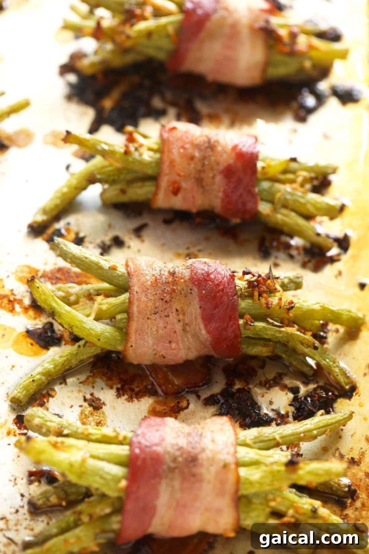 Freshly Baked Bacon Wrapped Green Beans A baking sheet filled with crispy, golden-brown bacon wrapped green beans, freshly baked and glistening, ready to be removed from the oven and served.