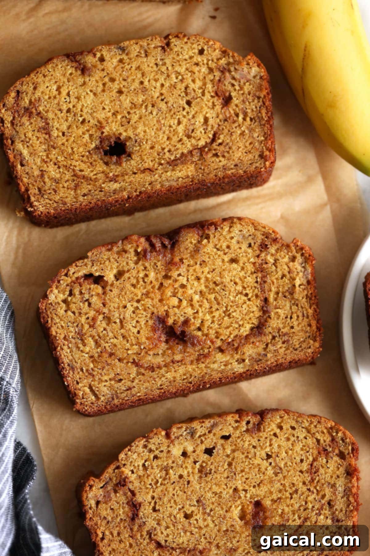 Heavenly Cinnamon Swirl Banana Bread 8 Multiple slices of cinnamon swirl banana bread arranged on parchment paper, ready for serving or storage.