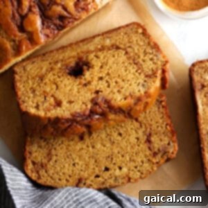 Heavenly Cinnamon Swirl Banana Bread 9 A golden-brown loaf of cinnamon swirl banana bread on a cutting board, ready to be sliced.