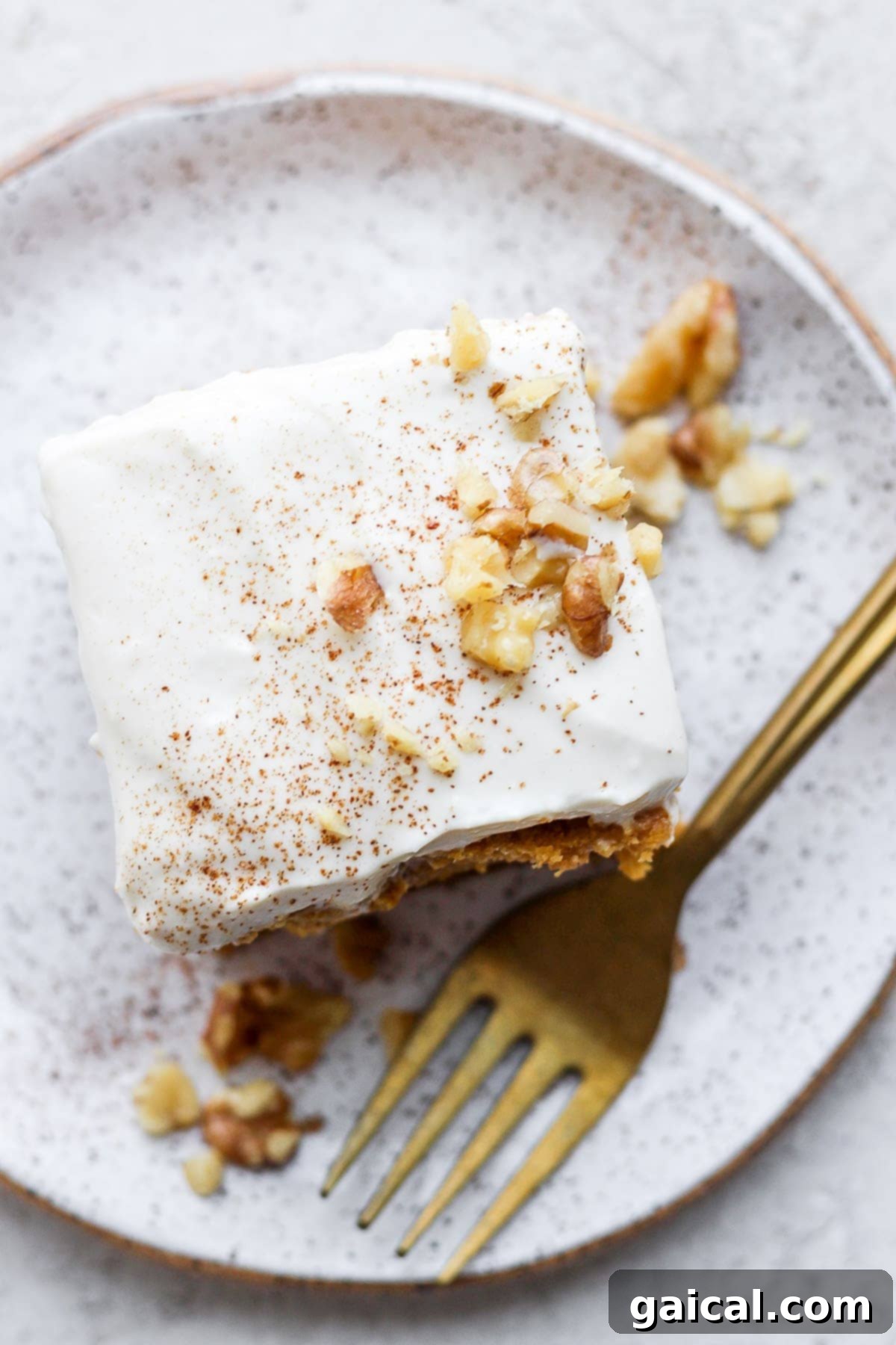 Guilt-Free Cream Cheese Frosting 2 A generous slice of pumpkin cake topped with a thick, creamy layer of healthy Greek yogurt cream cheese frosting, resting on a white plate with a fork.