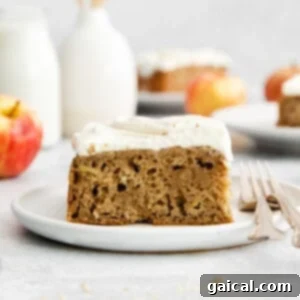 A delightful slice of apple cake generously topped with healthy Greek yogurt cream cheese frosting, ready to be enjoyed, showcasing the frosting's perfect spreadability.