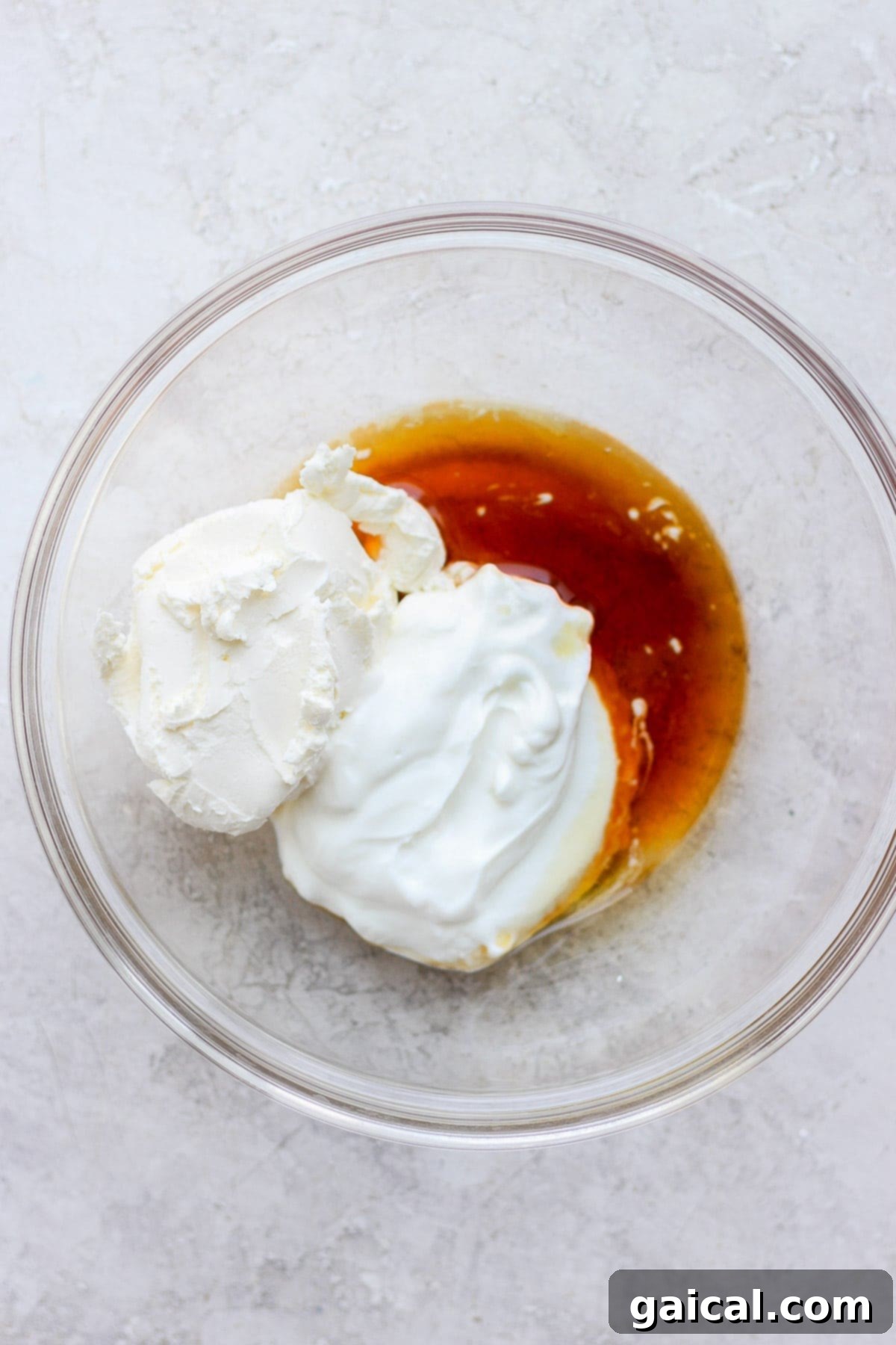 Guilt-Free Cream Cheese Frosting 4 A large mixing bowl containing all the combined ingredients for healthy cream cheese frosting – softened cream cheese, Greek yogurt, maple syrup, and vanilla extract – ready for whipping.