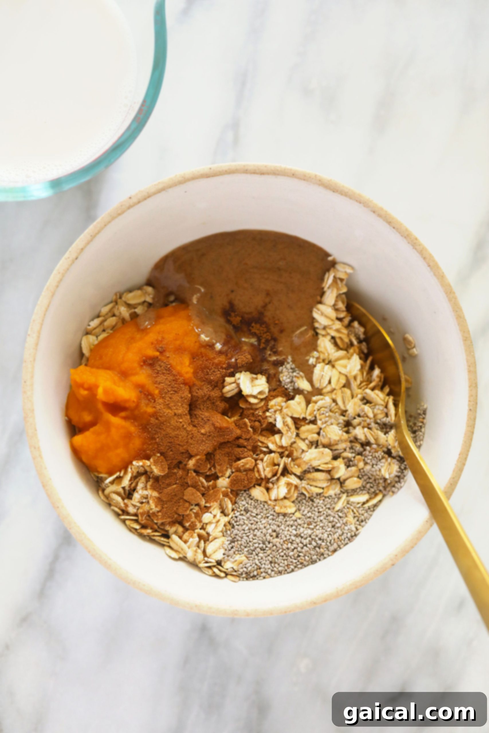 Ingredients for pumpkin overnight oats laid out in a bowl, including oats, pumpkin puree, and spices.