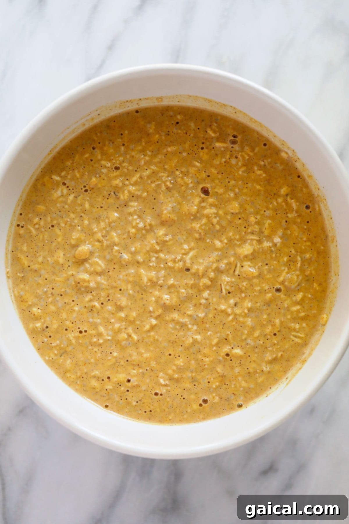 All ingredients for pumpkin overnight oats mixed together in a bowl before chilling.