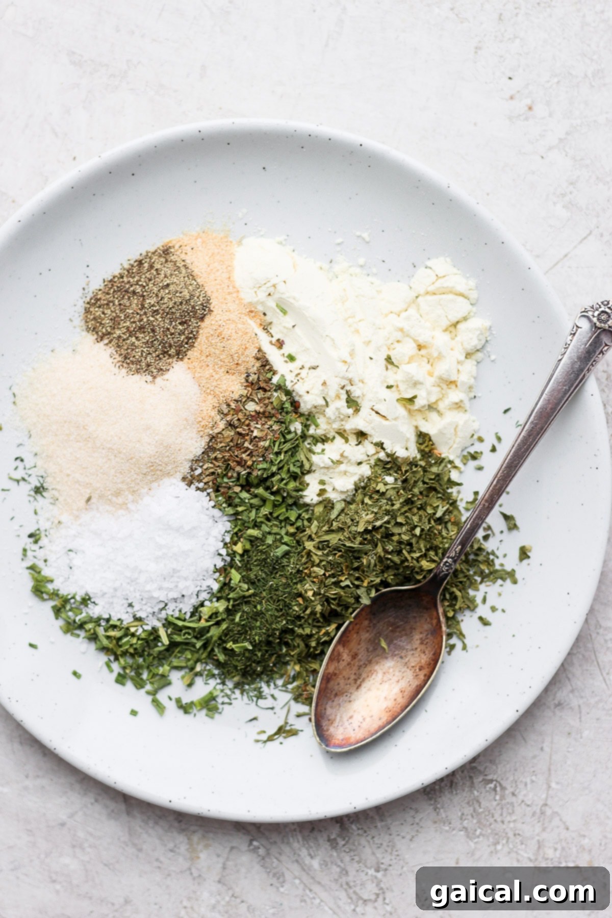 The best homemade ranch seasoning recipe on the internet. You'll want to have a jar of this ranching seasoning over any store-bought packet...trust me! Ranch spices on a plate, showcasing the individual dried herbs and powders before mixing.