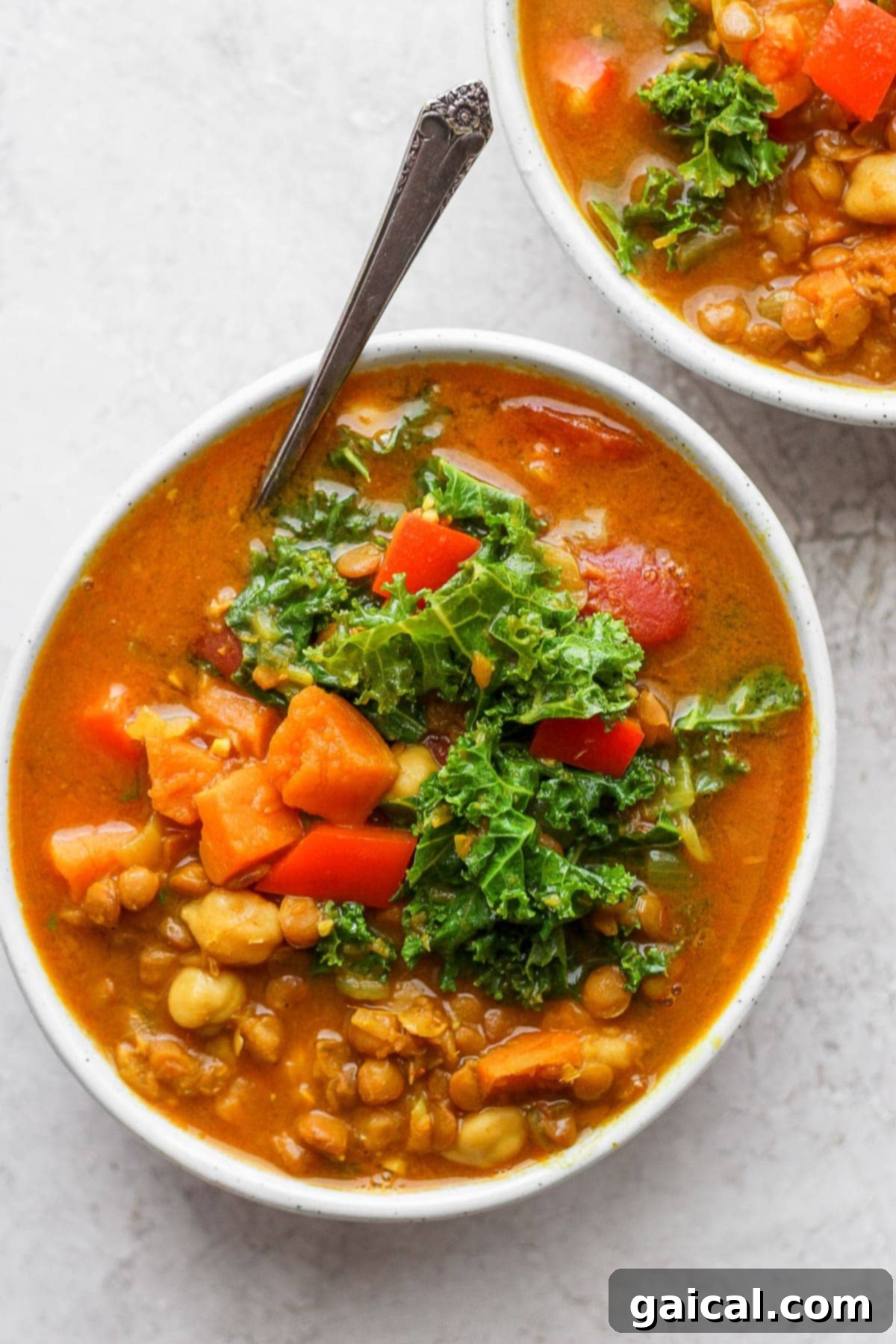 Two bowls of Instant Pot lentil soup garnished with fresh herbs.