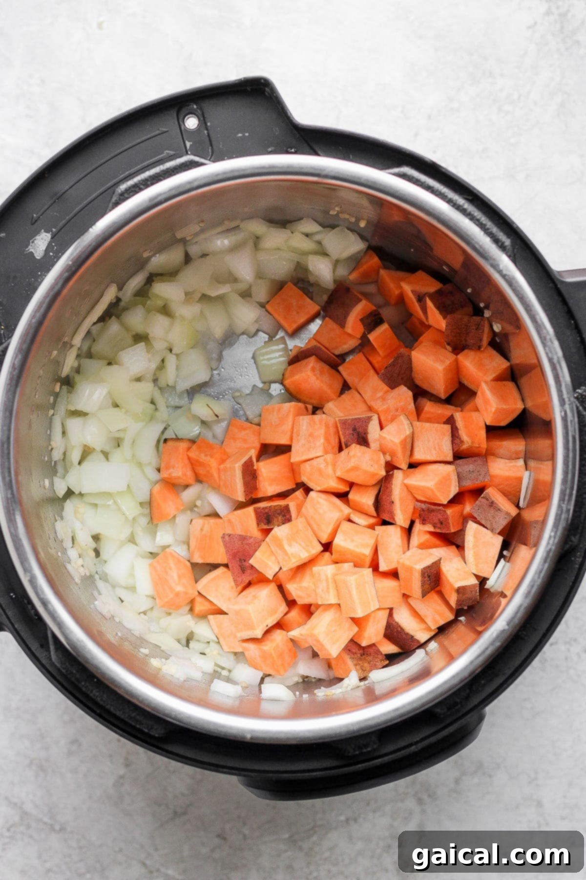 Sweet potatoes and onion sautéing in an Instant Pot pot.
