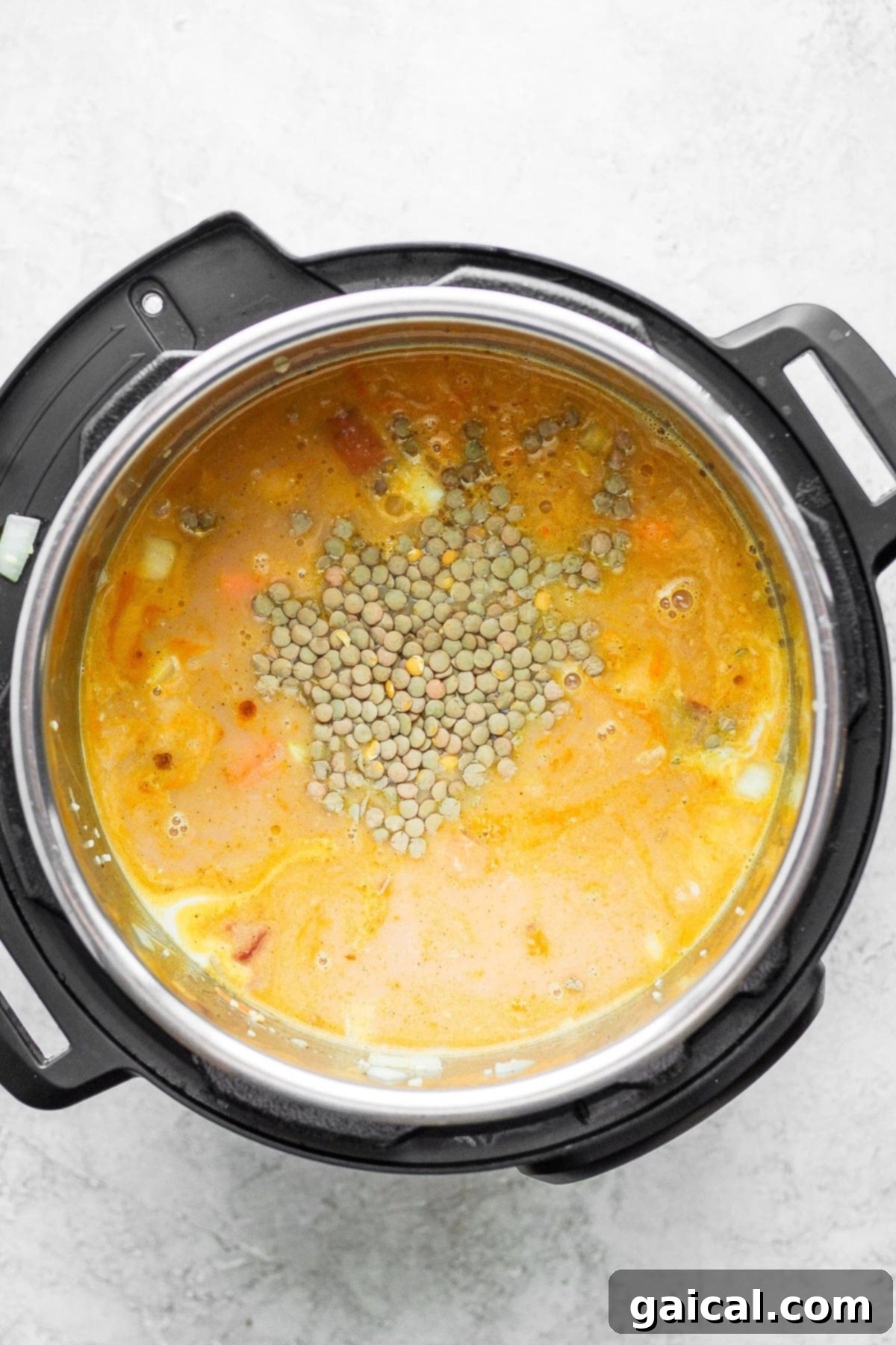 All the ingredients for Instant Pot lentil soup are combined in the pot before cooking.