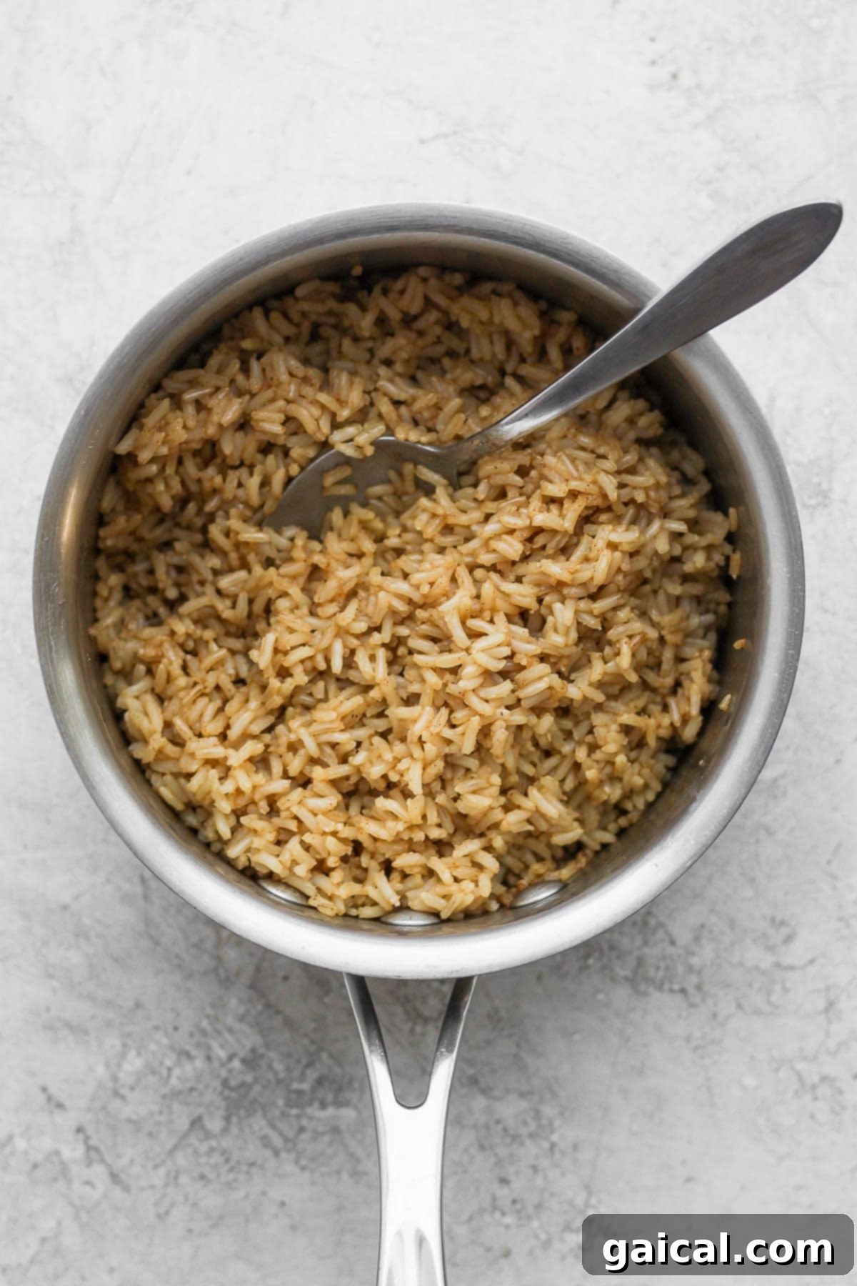 Brown rice cooking in a stock pot, absorbing broth and seasoning