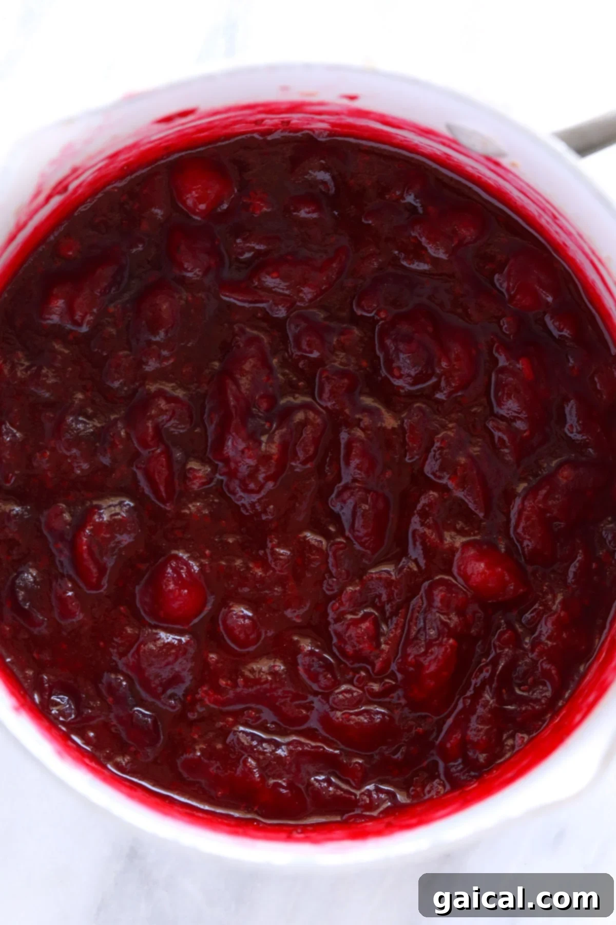 Freshly cooked lemon ginger cranberry sauce bubbling gently in a saucepan, showing its perfect consistency and vibrant color.