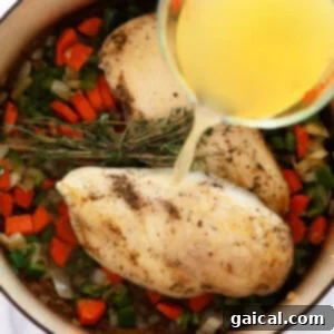 Hearty Chicken Wild Rice Soup 11 a person pouring olive oil into a pan with vegetables to prepare chicken wild rice soup.