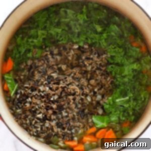 Hearty Chicken Wild Rice Soup 12 a chicken and wild rice soup with carrots and greens in it.