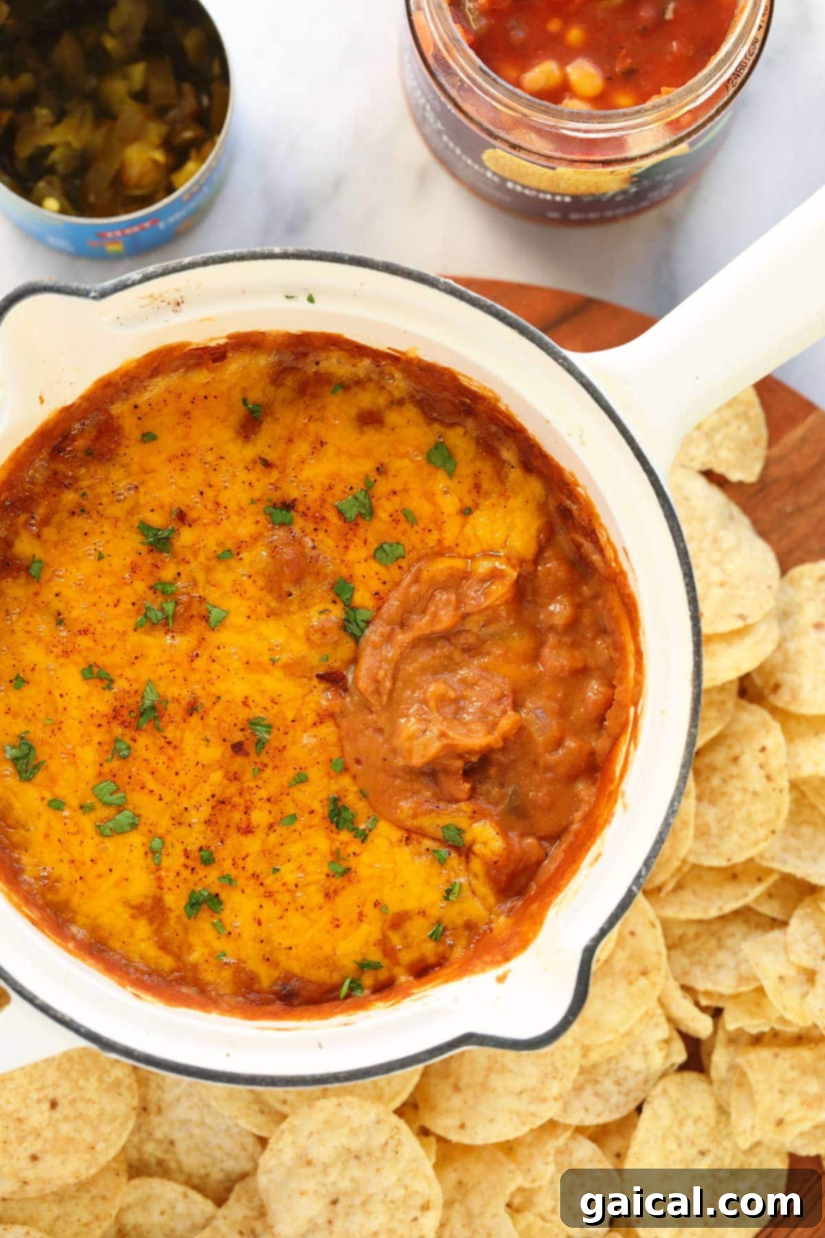 Delicious, gooey bean dip bubbling with melted cheese in a skillet, ready to be served hot. bean dip covered in melted cheese in a skillet