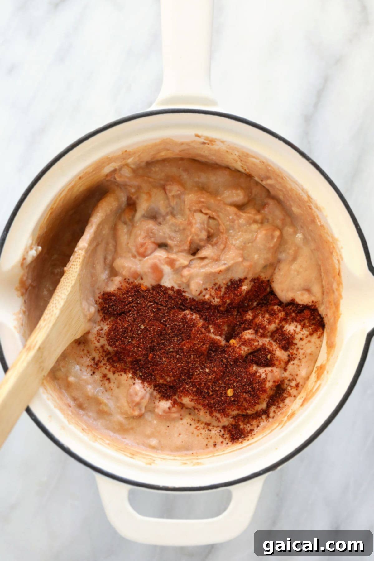 Hands actively mixing bean dip ingredients in a skillet, creating a harmonious blend of flavors. bean dip ingredients being mixed together in a skillet
