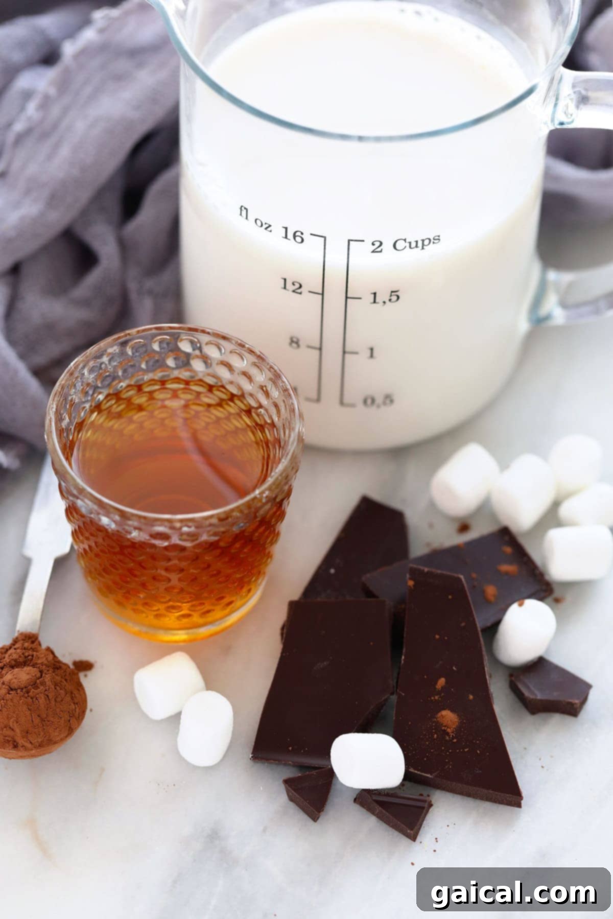 Essential Spiked Hot Chocolate Ingredients A selection of fresh ingredients including milk, dark chocolate, cocoa powder, maple syrup, and a bottle of bourbon, ready for making spiked hot chocolate.