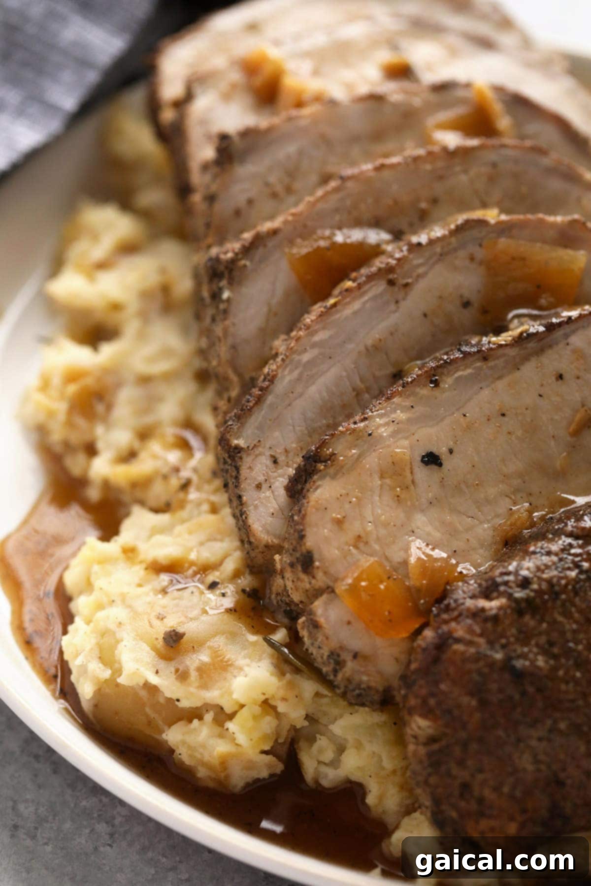 This is the most tender Slow Cooker Pork Loin roast recipe ever! It's served with potatoes and a savory gravy for the perfect meal. Enjoy! slow cooker pork loin sliced into perfect portions and richly covered in delicious gravy.